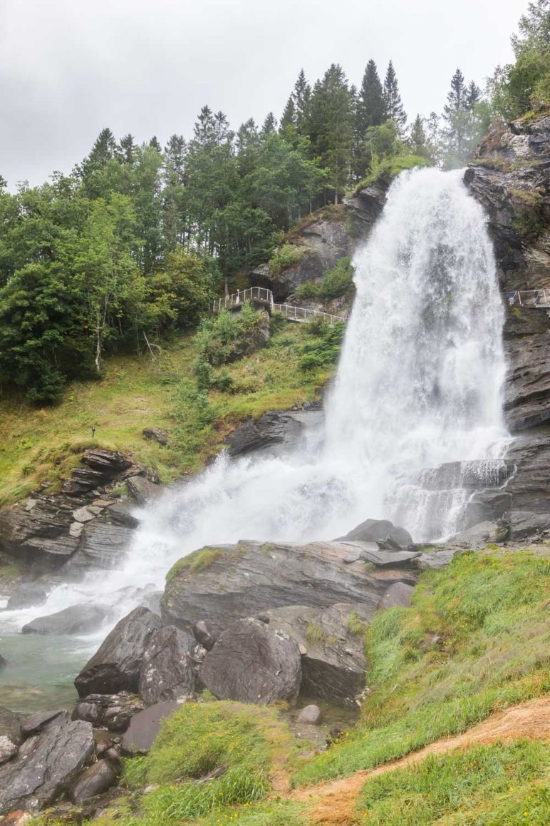 Skandinavien Roadtrip: Die Region Fjord Norwegen begeistert durch spektakuläre Fjorde, imposante Berge und tosende Wasserfälle. Ich habe euch Tipps für die schönsten Norwegischen Landschaftsrouten mit Stopps und Ausflugszielen an der Küste Fjord Norwegens zwischen Stavanger und Bergen mitgebracht. | Der Steinsdalsfossen an der Norwegische Landschaftsroute Hardanger bietet ein Blick hinter den Wasserfall.