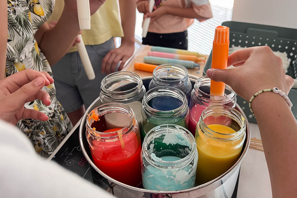 Kinder tauchen Kerzen in farbiges Wachs beim Dip Dye Kerzen Workshop Kindergeburtstag in Köln