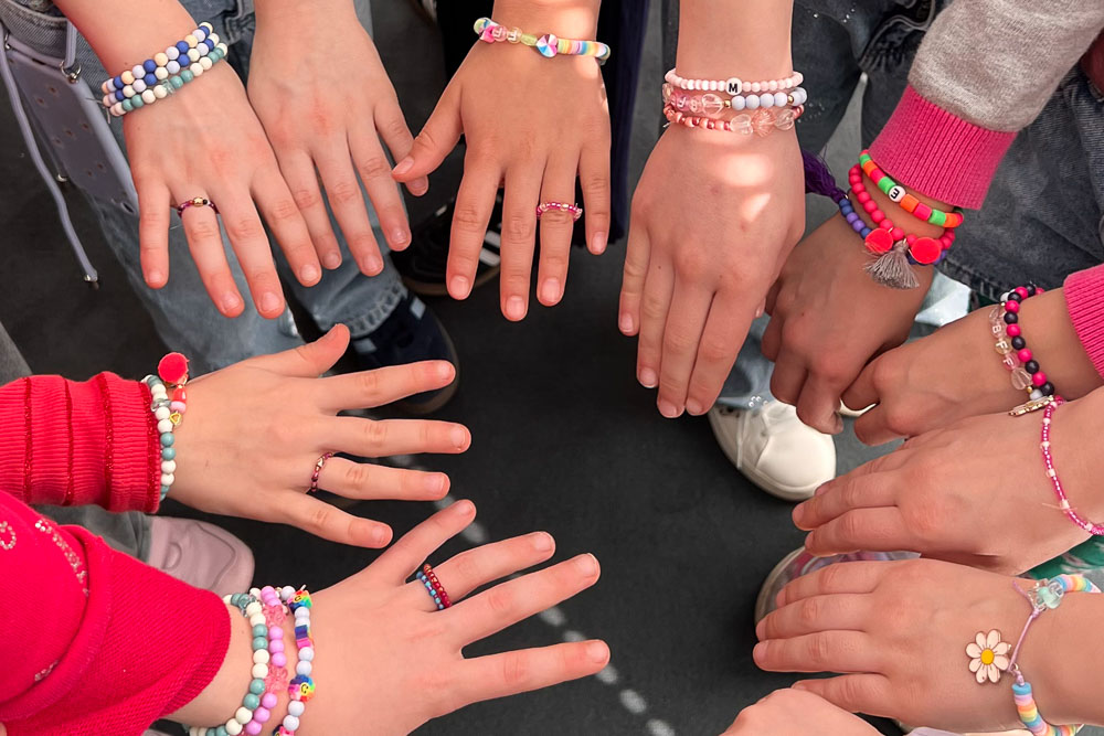 Kinder zeigen ihre Armbänder gemeinsam im Kreis beim Schmuckparty Kindergeburtstag in Köln