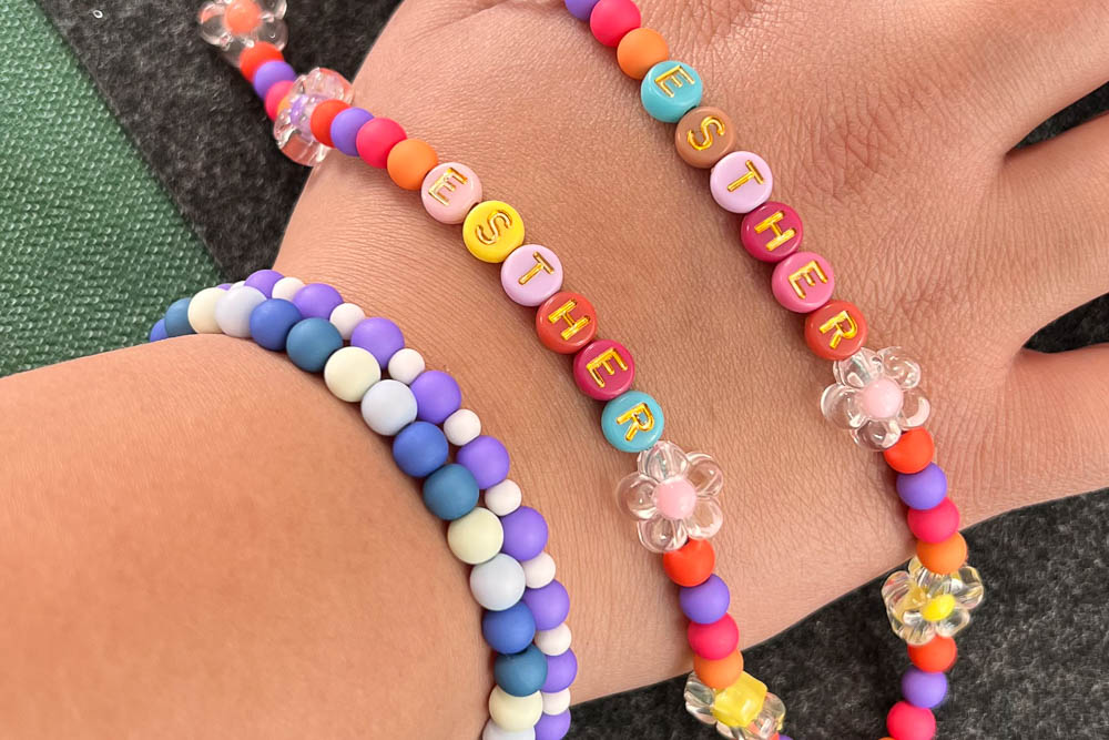 Kind zeigt selbst gestaltete Armbänder und Anhänger beim Schmuckparty Kindergeburtstag in Köln