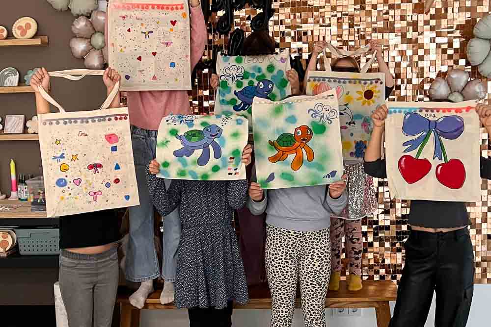 Kinder zeigen fertige Stoffbeutel beim Kindergeburtstag Workshop in Köln