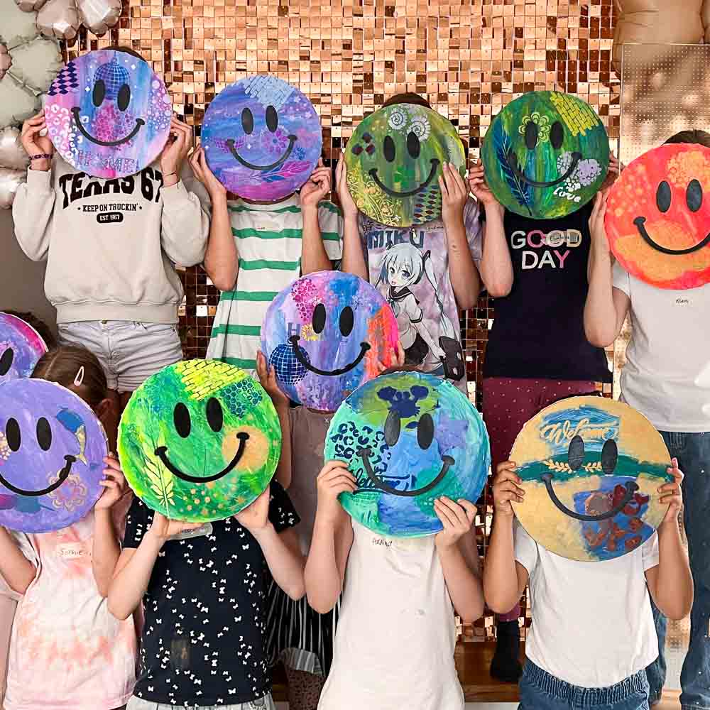 Kindergruppe zeigt ihre selbst gestalteten Happy Face Art Leinwände beim kreativen Kindergeburtstag im MrsBerry Studio bei Köln.