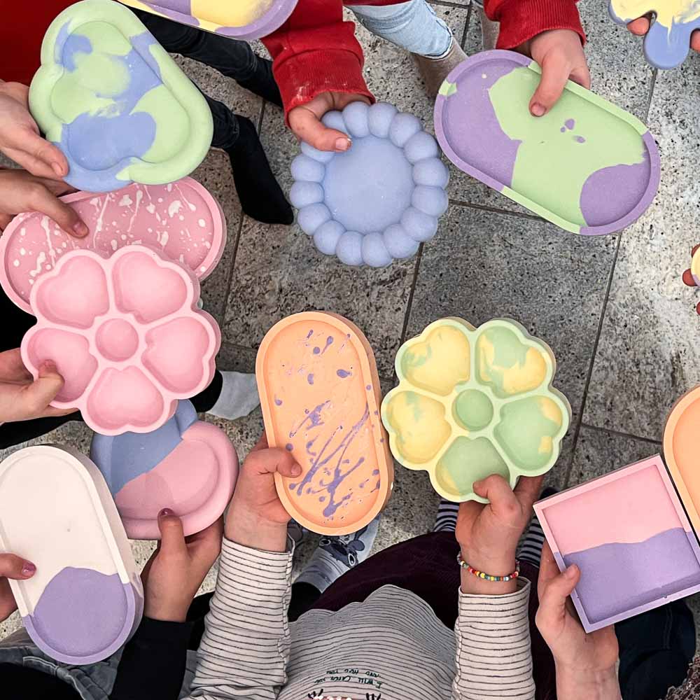 Kinder halten selbst gegossene Keramik Schmuckschalen in verschiedenen Formen und Pastellfarben bei einem Kindergeburtstag im MrsBerry Studio bei Köln.