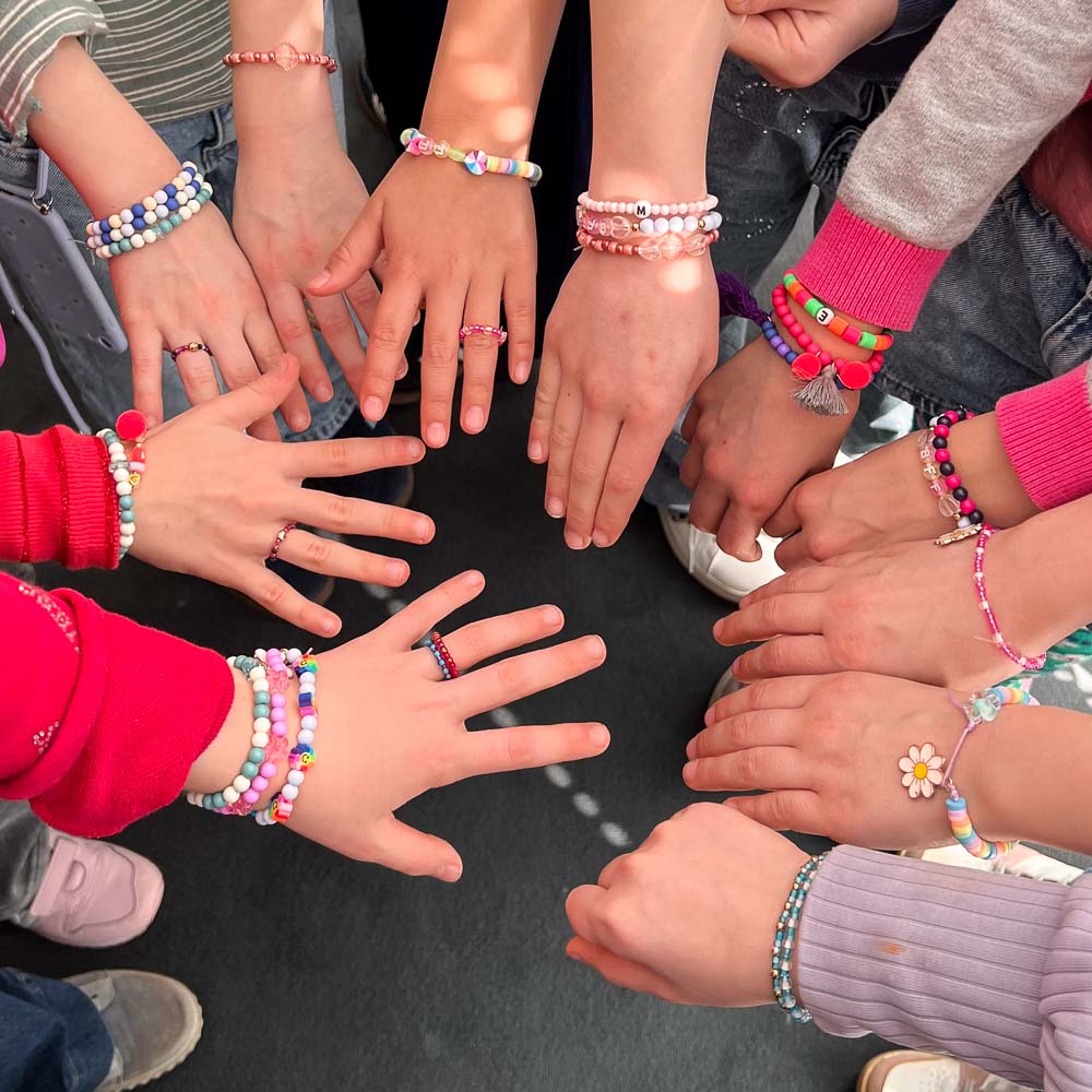 Kinder zeigen ihre selbst gestalteten bunten Perlenarmbänder bei einer Schmuckparty zum Kindergeburtstag im MrsBerry Studio bei Köln.