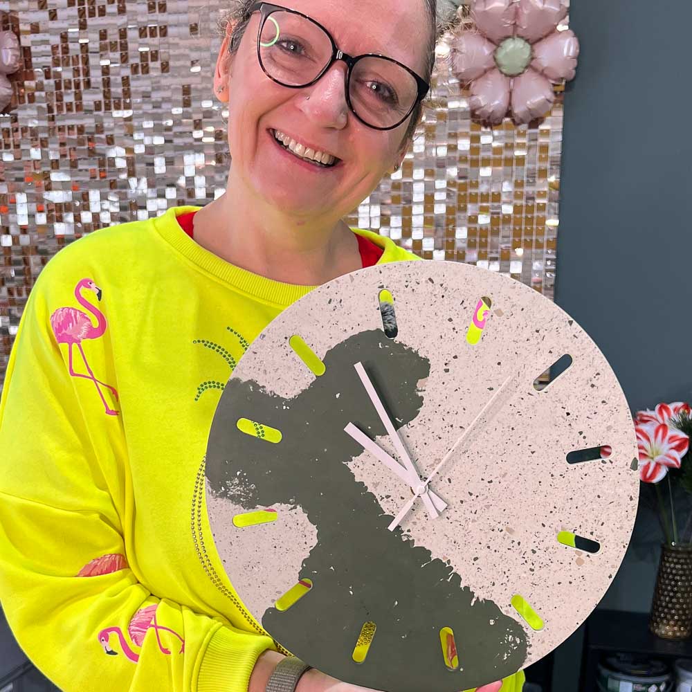 Hand hält eine selbst gegossene grüne Uhr mit Terrazzo-Muster aus dem Uhr Spezial Workshop